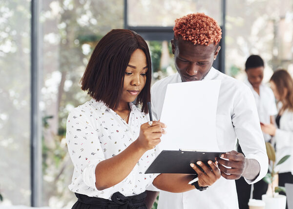 Holding notepad. Group of african american business people working in office together.